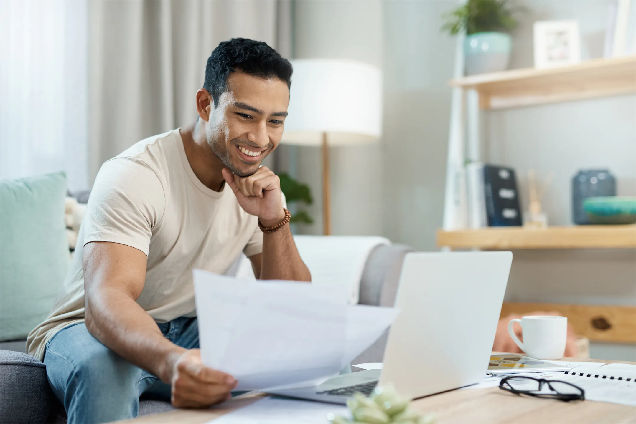 Young man reviewing financial documents at home on a laptop